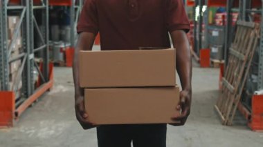 Karton kutular taşıyan ve depoda yürüyen tanınmayan Afro-Amerikan işçilerle yavaş takip.