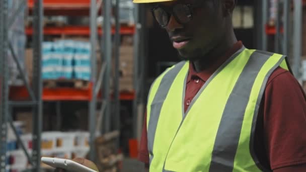 조끼를 모자를 태블릿을 사용하여 창고에서 카메라를 아프리카 미국인 근로자의 사진을 — 비디오