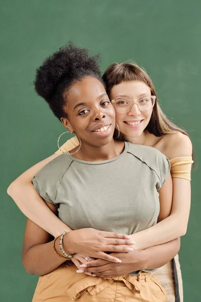 Cute girl in eyeglasses embracing her African girlfriend — Stock Photo, Image