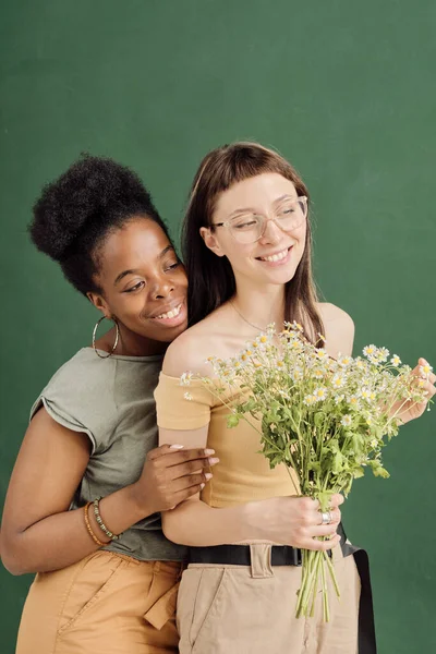 Deux jeunes rencontres lesbiennes romantiques avec des fleurs debout devant la caméra — Photo