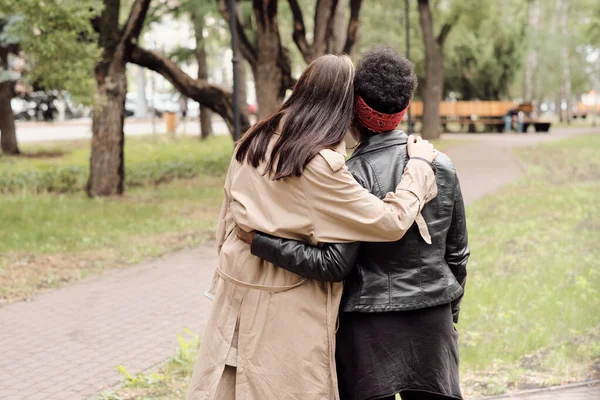 Vista trasera de dos mujeres jóvenes en ropa casual paseando por el parque — Foto de Stock