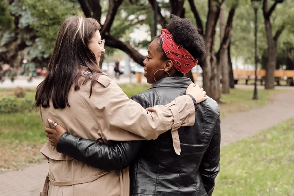 Visão traseira de jovens mulheres alegres interagindo durante o passeio no parque — Fotografia de Stock