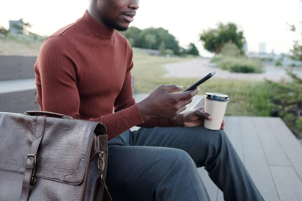 Manos de hombre joven de etnia africana desplazándose en el teléfono móvil — Foto de Stock