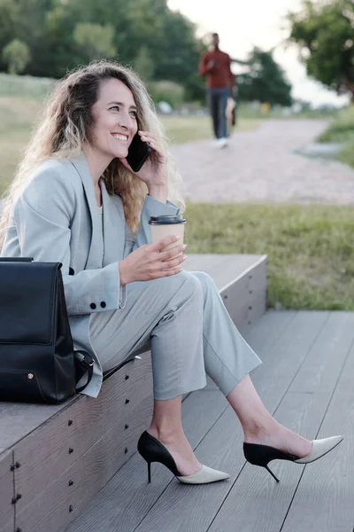 Jeune ouvrière blanche buvant et parlant sur smartphone — Photo