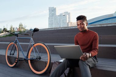 Dizüstü bilgisayarlı çağdaş iş adamı merdivenlerde oturuyor.