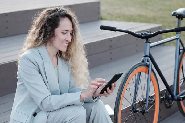 Feliz mulher de negócios loira rolando no smartphone ao ar livre — Fotografia de Stock