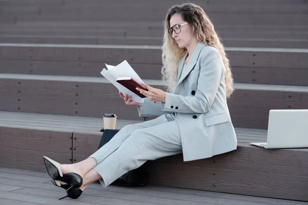 Allvarlig kvinnlig chef i formalwear tittar igenom papper — Stockfoto
