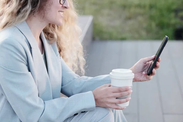 Ung affärskvinna som dricker och rullar i mobiltelefon utomhus — Stockfoto