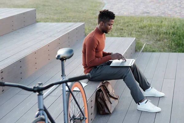 Jonge serieuze zakenman op zoek naar laptop scherm tijdens het typen — Stockfoto