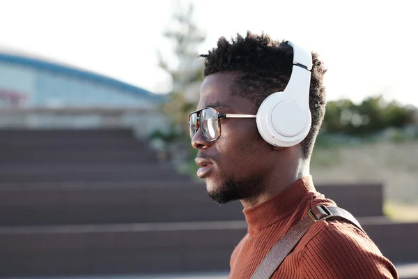 Joven hombre serio de etnia africana escuchando música en auriculares — Foto de Stock