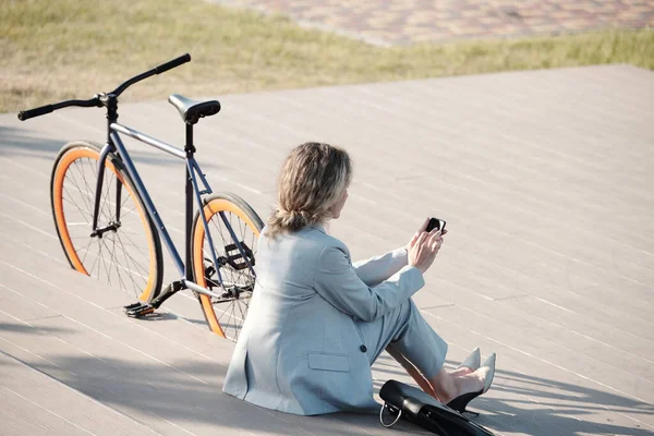 Rückansicht einer eleganten Geschäftsfrau, die im Smartphone scrollt — Stockfoto