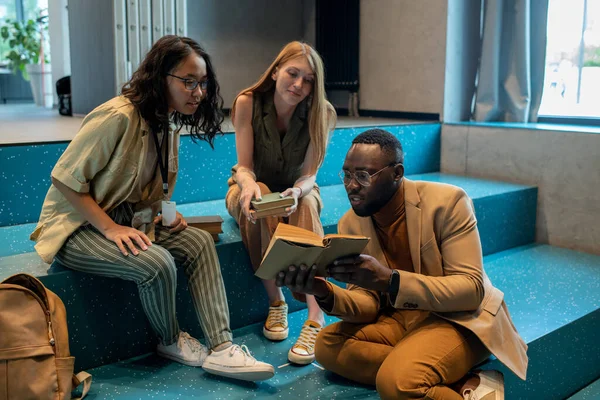 Jonge Afrikaanse man toont interesse tekst in boek aan zijn groepgenoten — Stockfoto