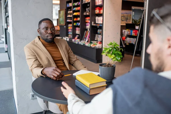 Jonge Afrikaanse zakenman kijkt naar collega tijdens interactie — Stockfoto