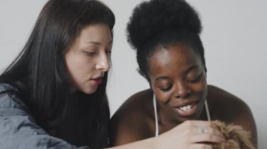 Yavaş yavaş mutlu lezbiyen çifti izliyorlar yatakta oturup gülümsüyorlar ve sevimli köpekleri okşuyorlar.