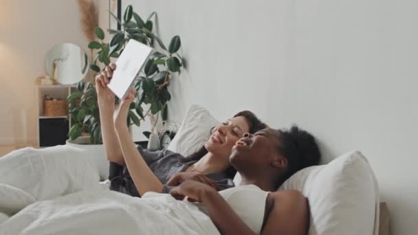 Handheld Slowmo Shot Happy Multi Ethnic Female Couple Lying Bed — Stock Video