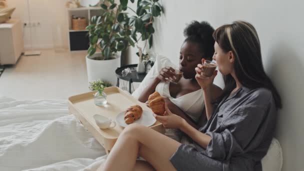 白人和非洲裔美国妇女手持式慢车 她们坐在舒适的公寓里 享受着早餐 — 图库视频影像
