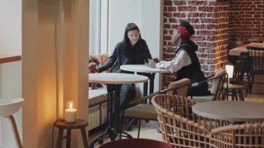 Kahve masasında oturup muhabbet eden sevimli köpekleri olan neşeli lezbiyen çiftin el kameraları.