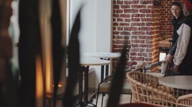 Kafedeki masada oturan mutlu Afro-Amerikan kadın ve Kafkasyalı kız arkadaşının el kamerasıyla takip edilmesi.