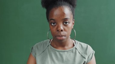 Yüzük küpeli güzel Afro-Amerikan kadının, koyu yeşil arka planda kameraya poz verirken çekilmiş portresi.