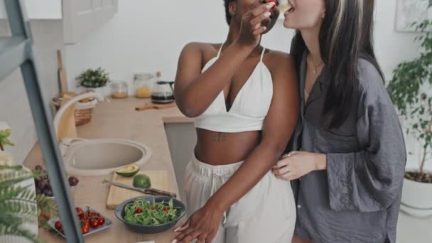 早上在厨房准备早餐的时候 一个快乐的非洲裔美国女人一边给女朋友的西红柿喂食 一边与她调情和跳舞 拍了张慢镜头 — 图库视频影像