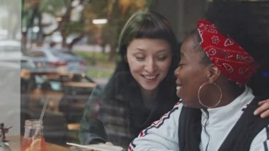 Kafenin penceresinden ağır çekim yapan mutlu eşcinsel çift buluşmalarının tadını çıkarırken gülüp sohbet ediyorlar.