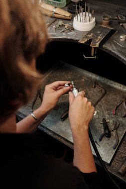 Atölyede gümüş yüzük cilalayan tanınmayan imalatçı kuyumcunun omuzlarının üstünden.