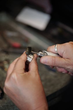 Atölyede gümüş mücevher yaparken aşındırıcı cilalama kullanan bir kuyumcunun elleri