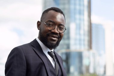 Resmi giyinmiş genç Afrikalı iş adamı kameraya bakıyor.