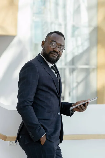 Mladý vousatý podnikatel v brýlích a formalwear drží digitální tablet — Stock fotografie