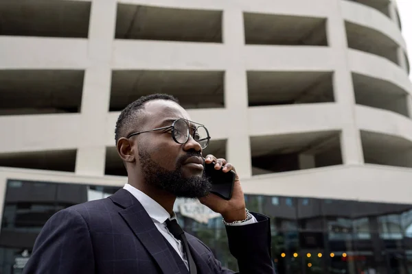 Joven empresario africano serio sosteniendo teléfono inteligente de oído — Foto de Stock