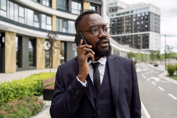 Jovem corretor confiante com smartphone pelo cliente de consultoria de orelha — Fotografia de Stock