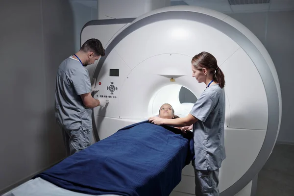 Ung assistent förbereder liten flicka för MRI scan undersökning — Stockfoto
