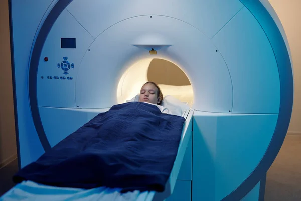 Liten flicka som ligger på långa medicinska bord när du flyttar in i MRI scan maskin — Stockfoto