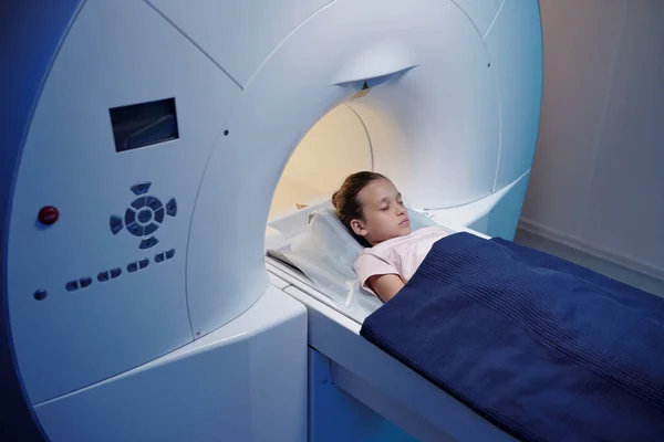 Liten flicka med slutna ögon rör sig in i MRI scan maskin — Stockfoto