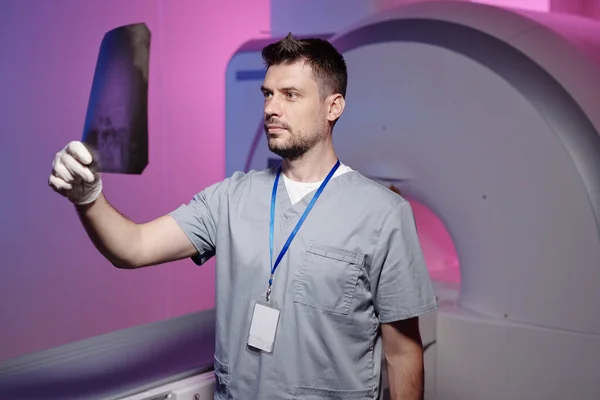 Ung seriös läkare tittar på röntgenresultat per arbetsplats — Stockfoto