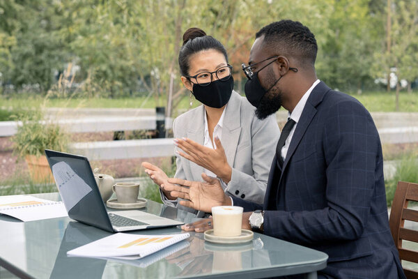 Два уверенных белых воротничка в масках обсуждают новый бизнес-проект