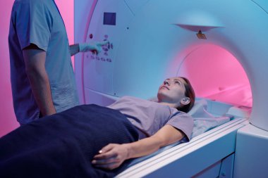 Tıbbi masadaki genç kadın MRI tarama makinesine giriyor.