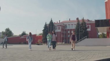 Bir grup ortaokul öğrencisinin okul binasından uzaklaşırken düşük açılı görüntüsü.