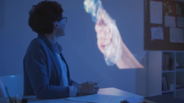 Средний Снимок Женщины Учителя Очках Сидящей Столом Темном Классе Говорящей — стоковое видео