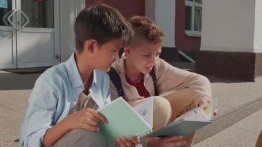 12 yaşındaki ve 13 yaşındaki çocukların ortaokul binasının merdivenlerinde oturup ödev cevaplarını karşılaştırırken çekilmiş bir fotoğrafı.