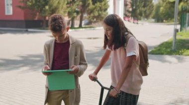 Mobiletle gezen 13 yaşındaki bir kızın okul bahçesinde tablette oynayan oğlanı izlediği el kamerası görüntüsü.