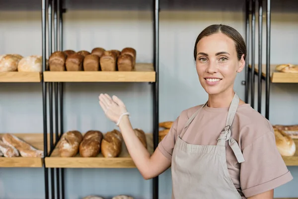 Unga leende kontorist visar bageri sortiment — Stockfoto