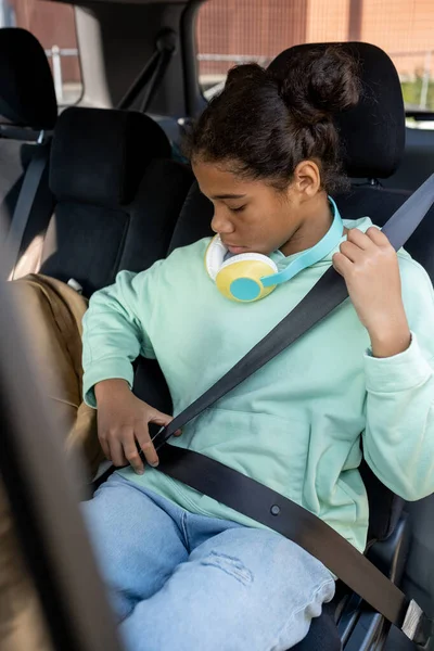 Schattig schoolmeisje bevestiging veiligheidsgordel terwijl zitten in de auto — Stockfoto