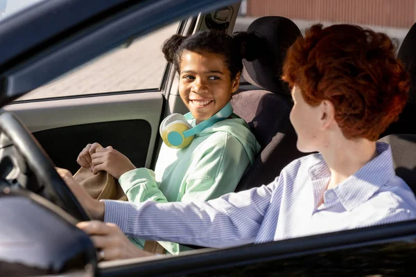 Heureuse fille métissée regardant jeune femme en voiture — Photo