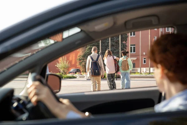 Jonge vrouw sititng in auto en kijken naar groep van schoolkinderen — Stockfoto