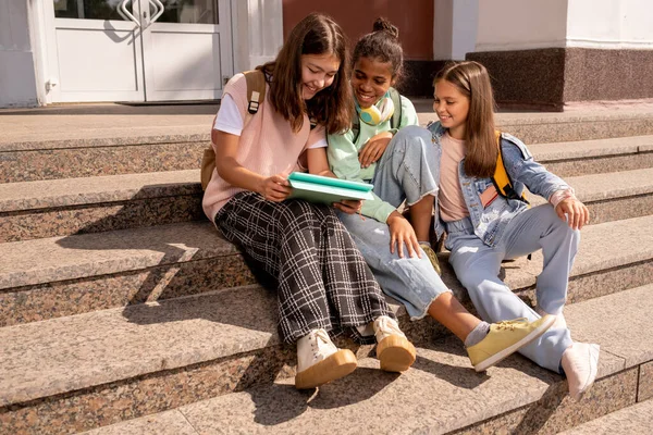 Colegialas contemporáneas discutiendo notas en copybook — Foto de Stock