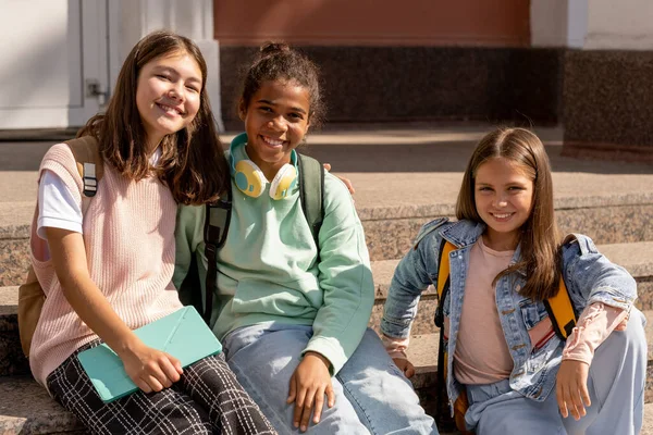 Три радісні і дружні школярки в повсякденному одязі насолоджуються сонячним днем — стокове фото