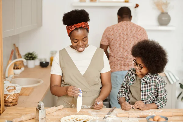 Lindo chico ayudando a su mamá con pastelería casera en la cocina —  Fotos de Stock