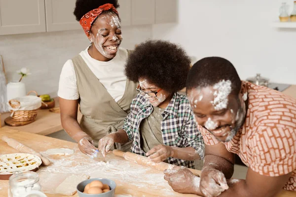 Pais alegres e seu filho se divertindo enquanto cozinha pastelaria — Fotografia de Stock