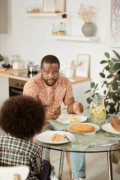 Contemporaneo giovane guardando il suo piccolo figlio mentre mangia la pasta — Foto Stock